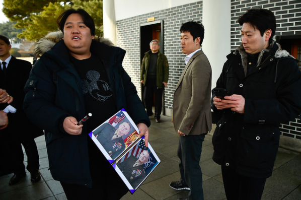 A South Korean man wearing a Mickey Mouse shirt holds photos of Secretary Mattis along with a pen, hoping to get an autograph following the wreath laying ceremony. 