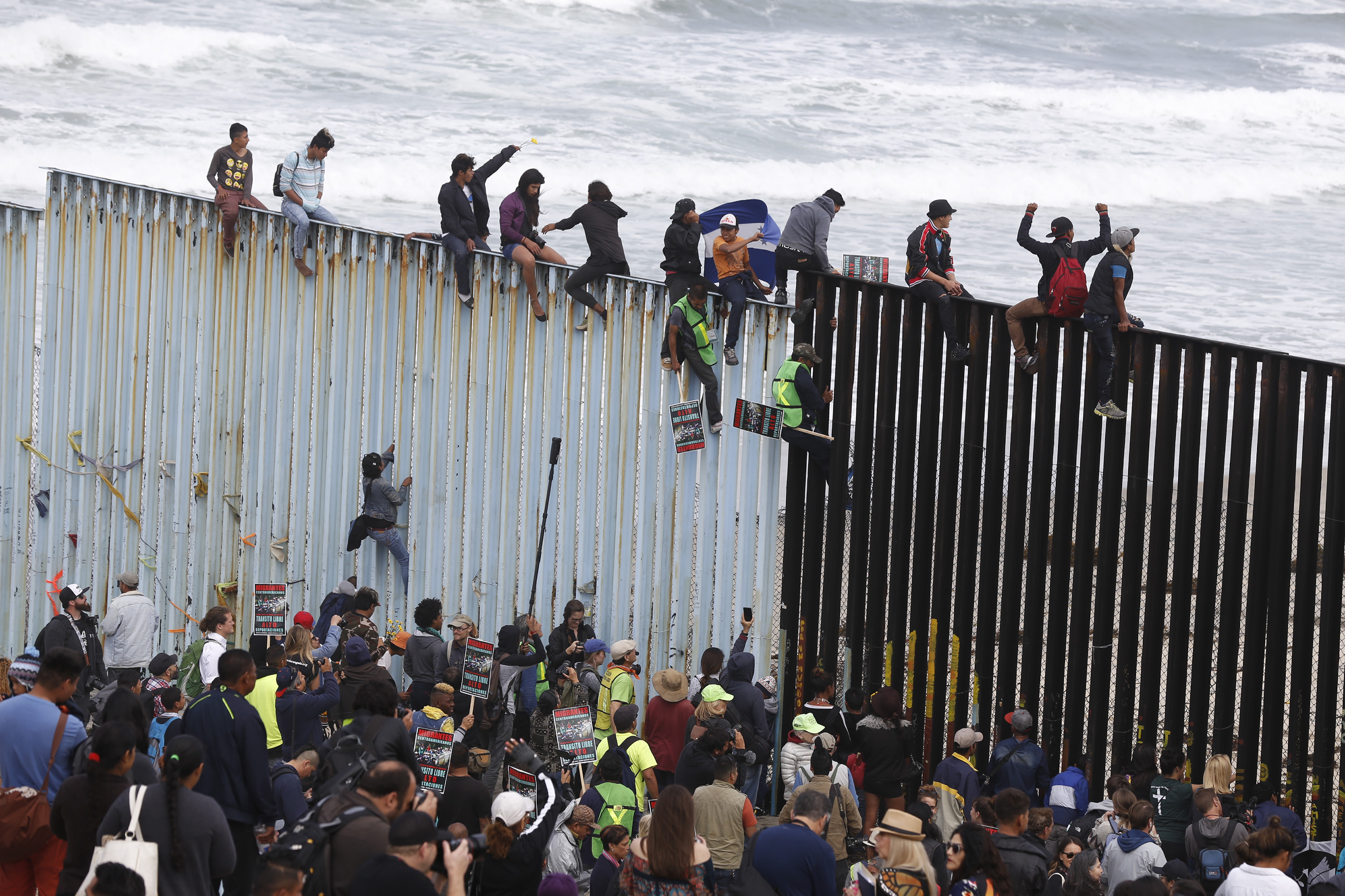 Migrants from 'caravan' scale border wall in protest after denied entry ...