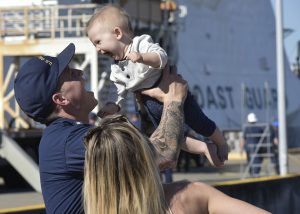 A crewmember from Coast Guard Cutter Bertholf reunites with his wife and child after the cutter returned to homeport at Coast Guard Island in Alameda, Calif., Oct. 24, 2017.